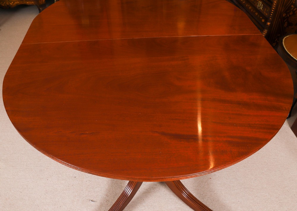 A large George IV Regency mahogany extended dining table featuring three pedestal supports with reeded legs and brass castors. View X