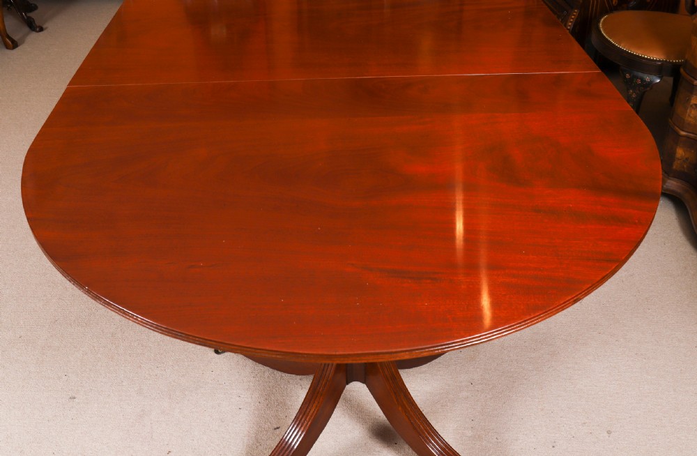 A large George IV Regency mahogany extended dining table featuring three pedestal supports with reeded legs and brass castors. View XI