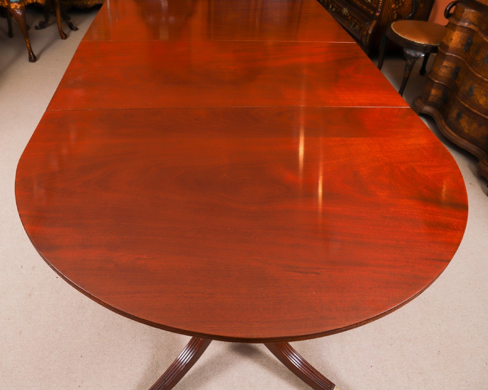 A large George IV Regency mahogany extended dining table featuring three pedestal supports with reeded legs and brass castors. View XIII