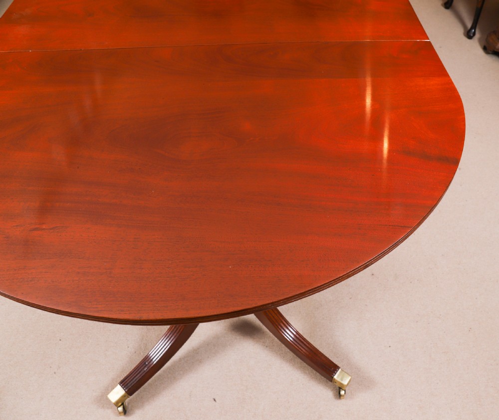 A large George IV Regency mahogany extended dining table featuring three pedestal supports with reeded legs and brass castors. View XV