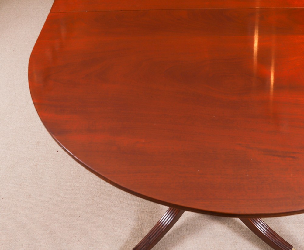 A large George IV Regency mahogany extended dining table featuring three pedestal supports with reeded legs and brass castors. View XVI