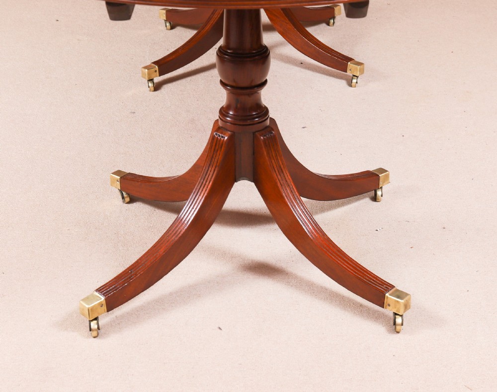A large George IV Regency mahogany extended dining table featuring three pedestal supports with reeded legs and brass castors. View XVIII
