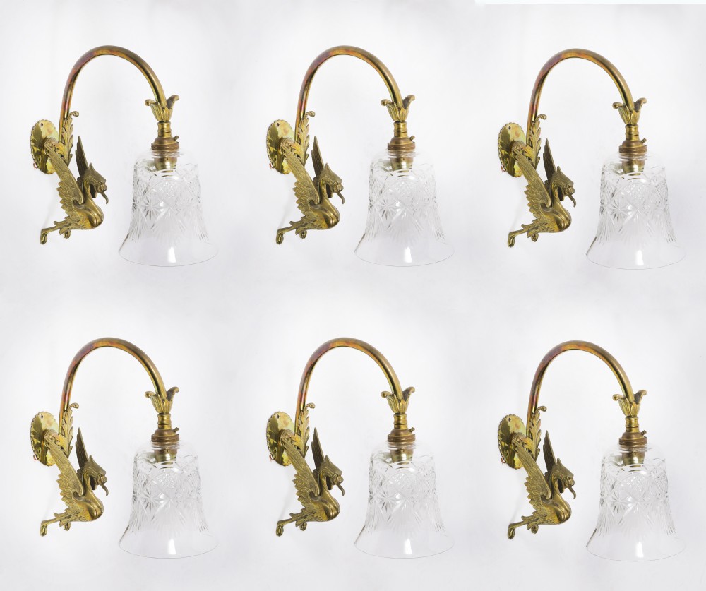 A set of six Neo-Classical brass wall sconces featuring sculpted griffin mounts, curved arms, and flared cut-glass bell shades.