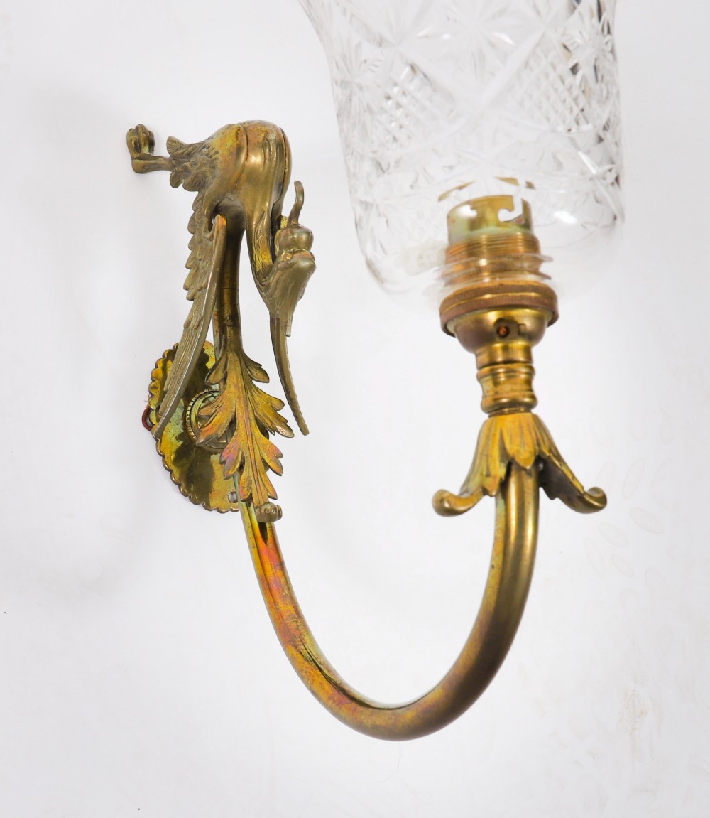 A set of six Neo-Classical brass wall sconces featuring sculpted griffin mounts, curved arms, and flared cut-glass bell shades. View VI