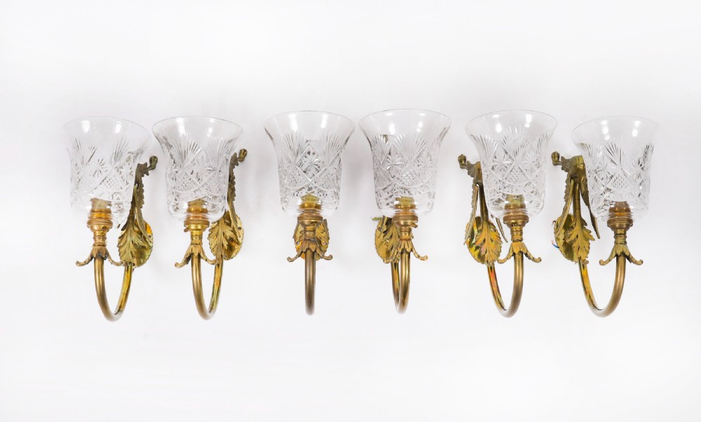 A set of six Neo-Classical brass wall sconces featuring sculpted griffin mounts, curved arms, and flared cut-glass bell shades. View VIII
