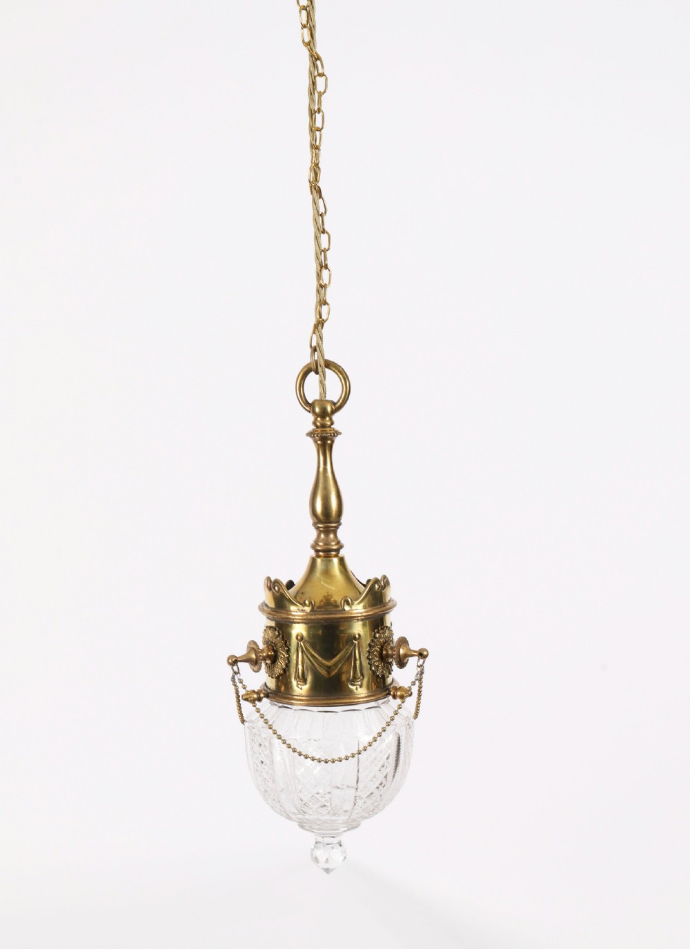 An antique Edwardian brass ceiling pendant light featuring a cast brass collar decorated with swag motifs and a cut crystal shade. View XVI