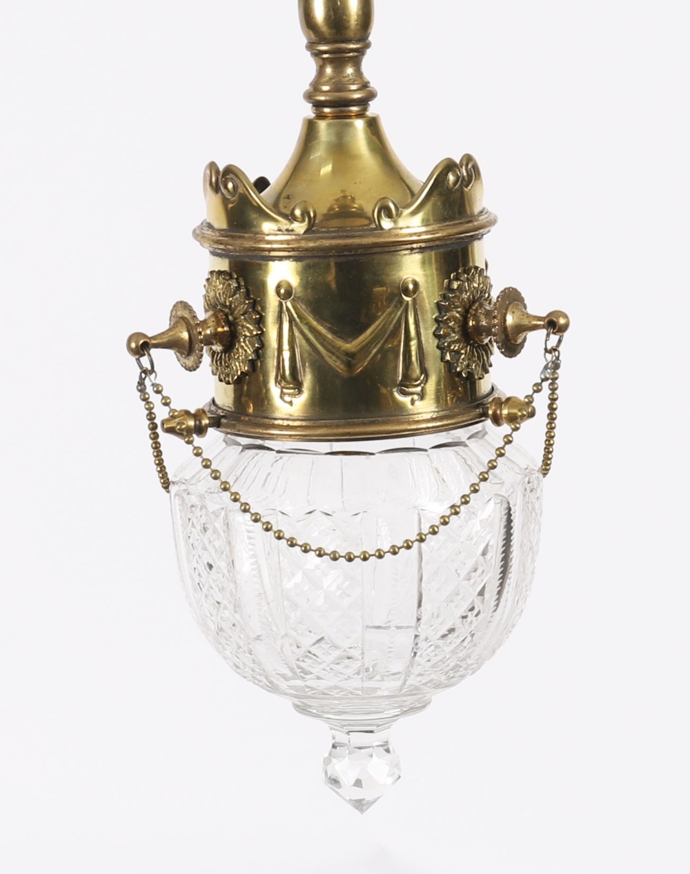 An Edwardian ceiling pendant light featuring an ornate brass gallery decorated with swags and rosettes, suspending a cut crystal glass globe with a pointed base finial.