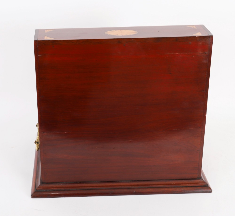 A 19th-century inlaid satinwood and mahogany tantalus containing three cut crystal decanters with faceted stoppers, a mirrored back interior, and a lower fold-out compartment with oval marquetry paterae. View VIII