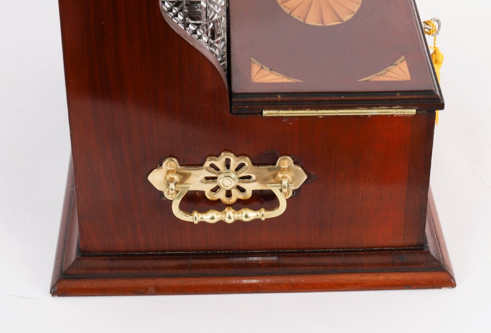 A 19th-century inlaid satinwood and mahogany tantalus containing three cut crystal decanters with faceted stoppers, a mirrored back interior, and a lower fold-out compartment with oval marquetry paterae. View IX