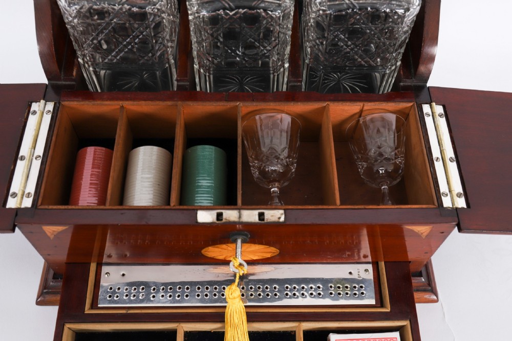 A 19th-century inlaid satinwood and mahogany tantalus containing three cut crystal decanters with faceted stoppers, a mirrored back interior, and a lower fold-out compartment with oval marquetry paterae. View XI