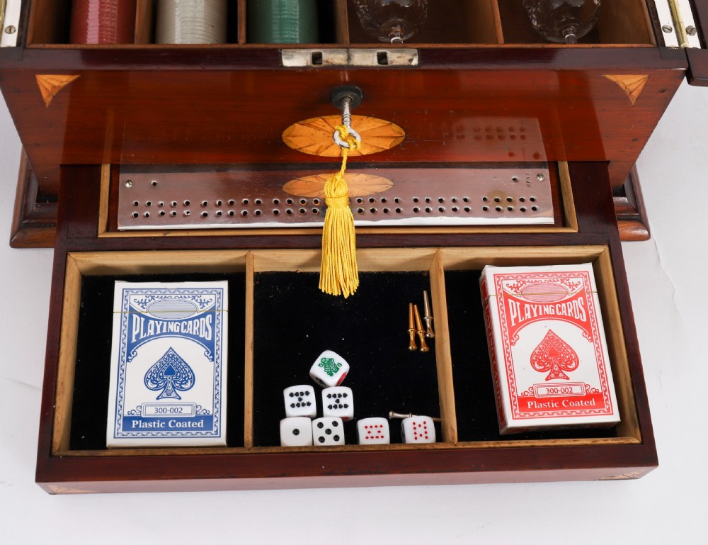 A 19th-century inlaid satinwood and mahogany tantalus containing three cut crystal decanters with faceted stoppers, a mirrored back interior, and a lower fold-out compartment with oval marquetry paterae. View XII
