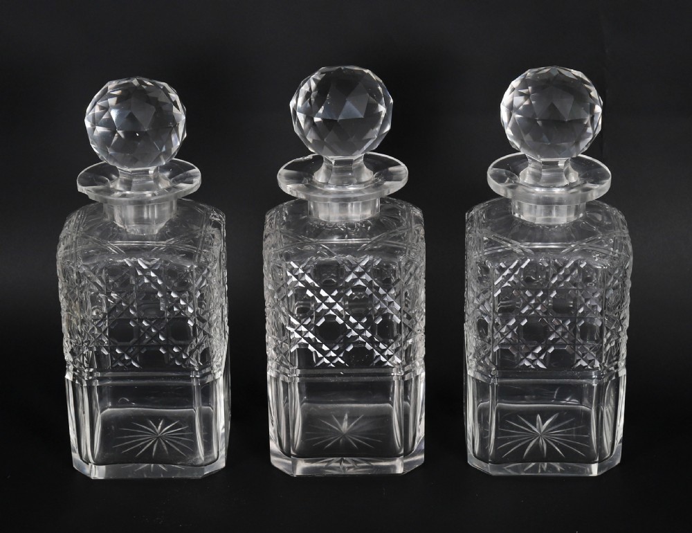 A 19th-century inlaid satinwood and mahogany tantalus containing three cut crystal decanters with faceted stoppers, a mirrored back interior, and a lower fold-out compartment with oval marquetry paterae. View XIV
