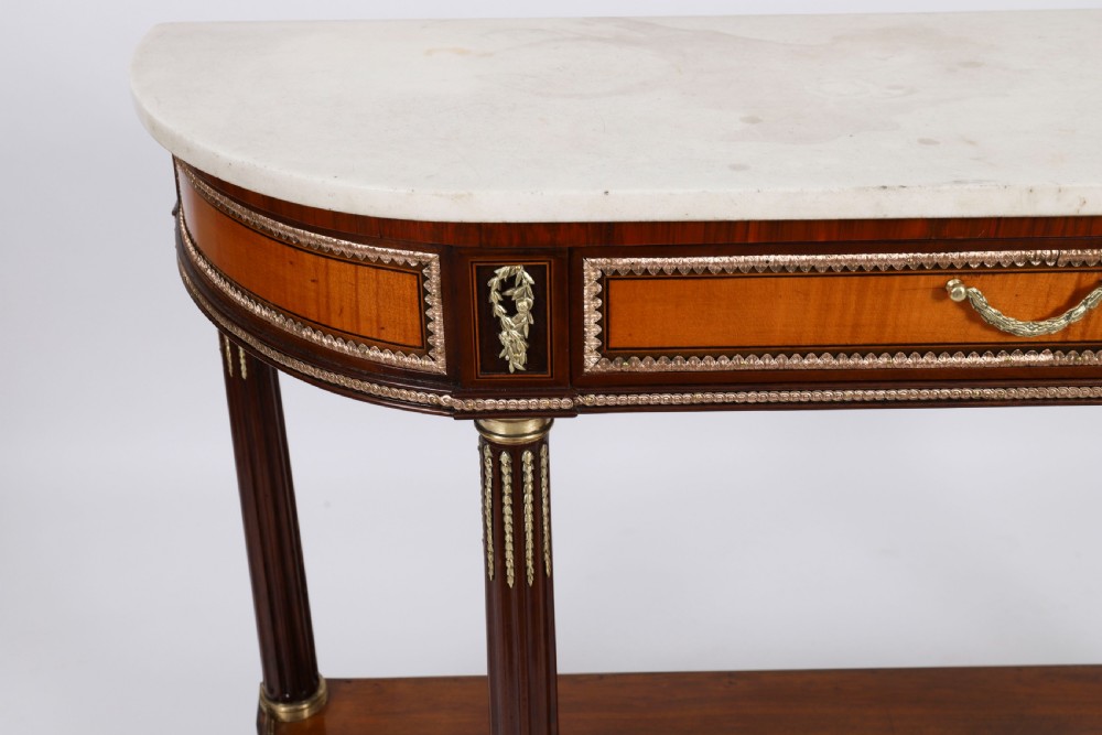 A pair of 19th-century French Louis XVI style demi-lune console tables with white Carrara marble tops, gilt bronze mounts, fluted legs, and undershelves. View VIII