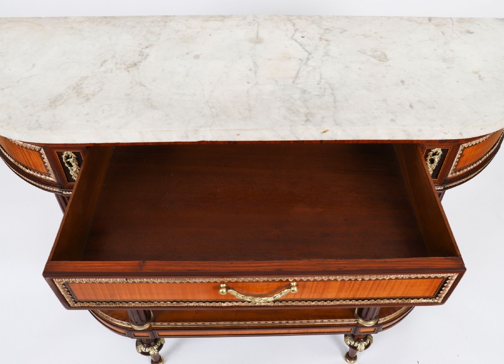 A pair of 19th-century French Louis XVI style demi-lune console tables with white Carrara marble tops, gilt bronze mounts, fluted legs, and undershelves. View X
