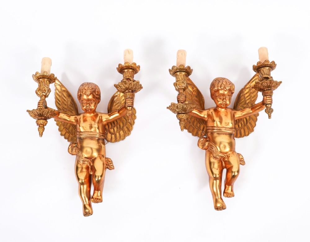 A pair of nineteenth-century gilt metal two-branch wall sconces featuring sculpted winged cherubs holding torch-shaped candleholders.