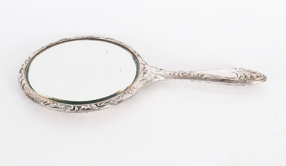 An Edwardian sterling silver hand mirror decorated with high-relief repousse cherubs amidst clouds and scrollwork. View VIII