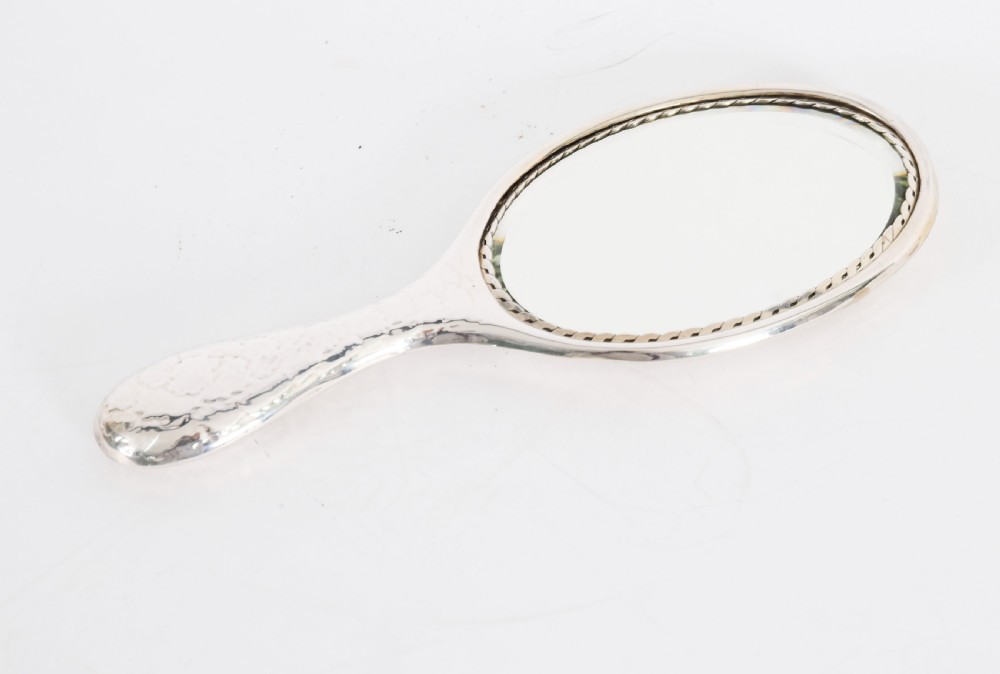 An Edwardian sterling silver hand mirror featuring embossed cherub heads and clouds on the back. View VI