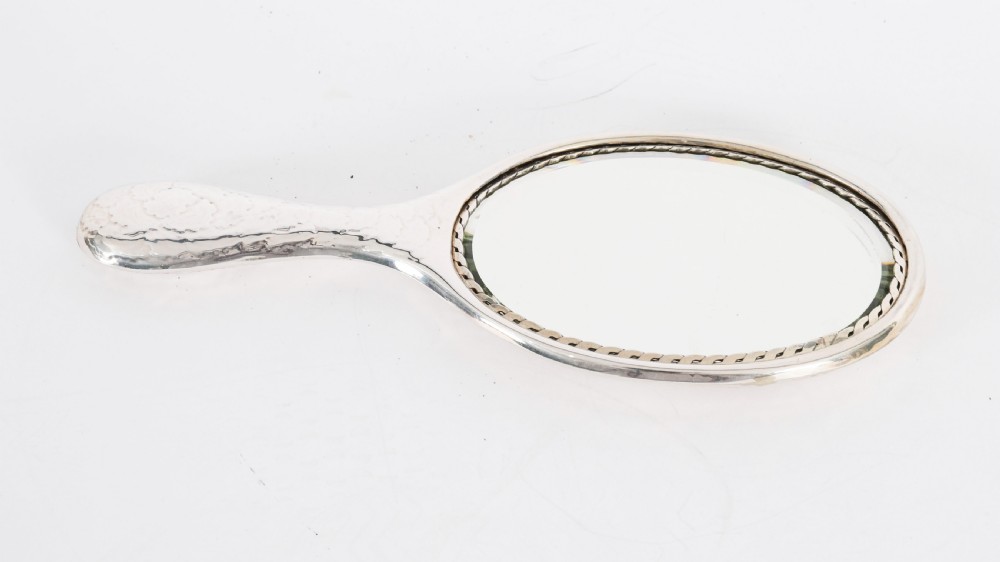 An Edwardian sterling silver hand mirror featuring embossed cherub heads and clouds on the back. View VIII
