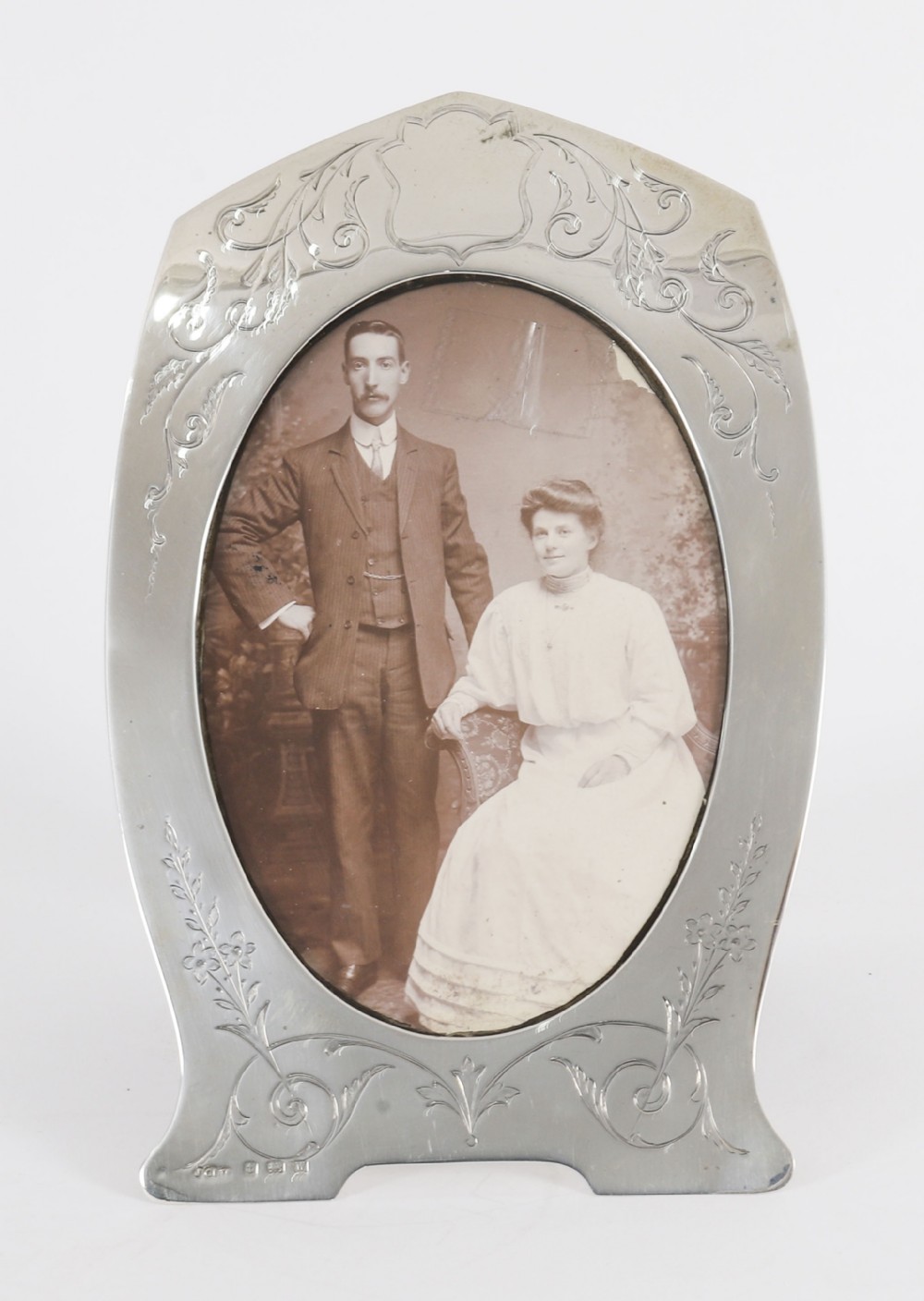 An arched sterling silver photo frame featuring engraved floral motifs around an oval picture aperture.