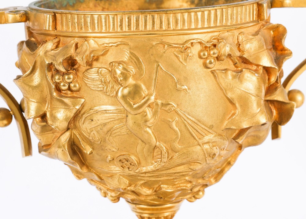 A pair of nineteenth-century French gilt bronze classical urns featuring relief carvings and scroll handles, mounted on dark green marble bases. View IV