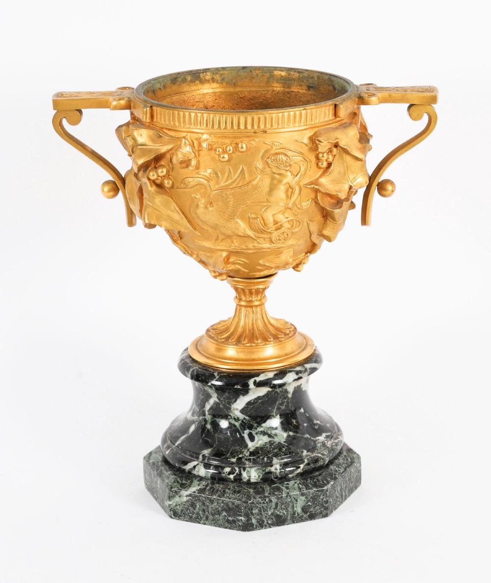 A pair of nineteenth-century French gilt bronze classical urns featuring relief carvings and scroll handles, mounted on dark green marble bases. View XI