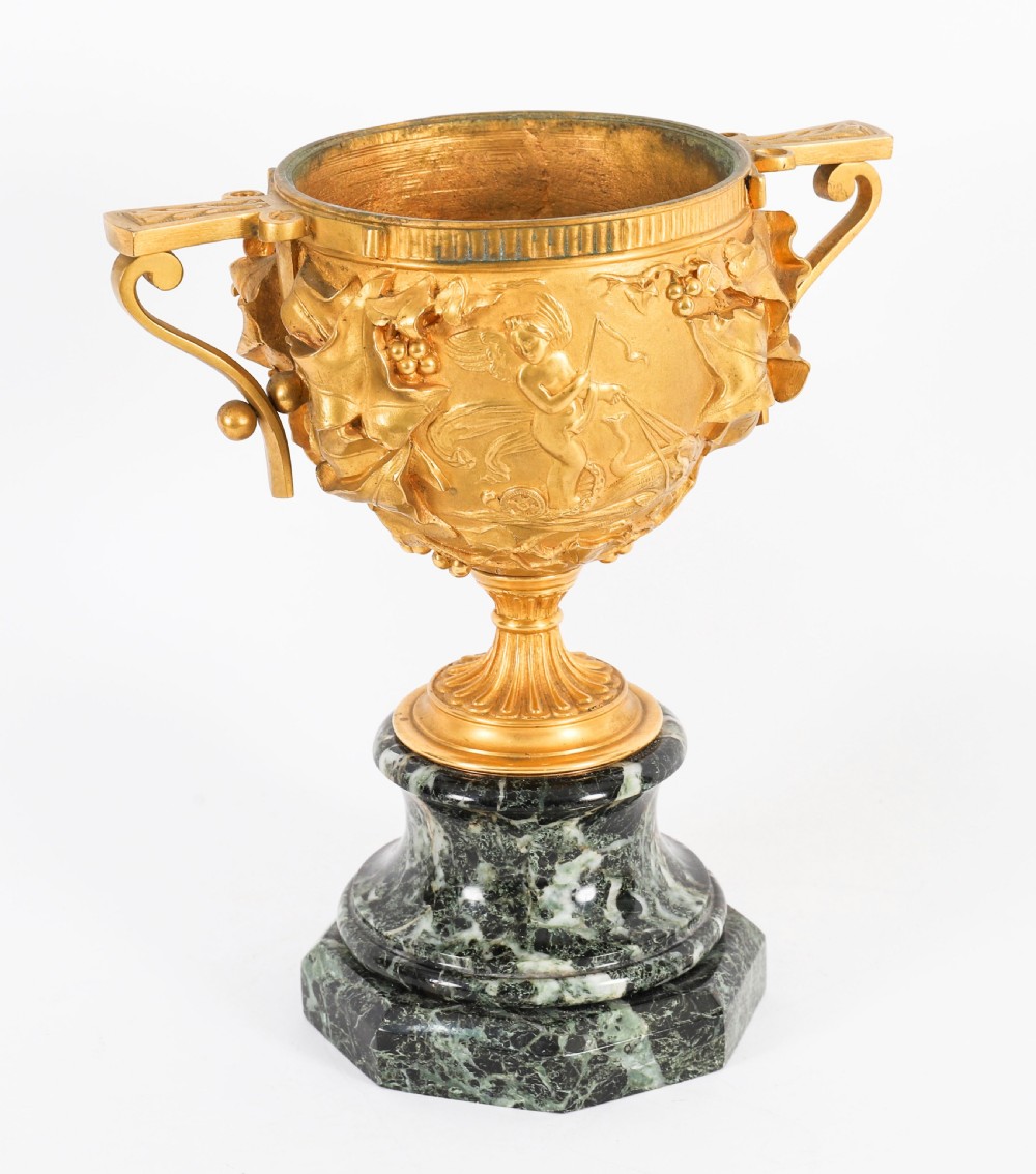 A pair of nineteenth-century French gilt bronze classical urns featuring relief carvings and scroll handles, mounted on dark green marble bases. View XV