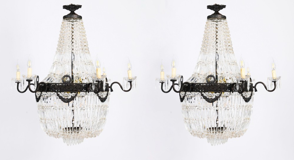 A pair of French Louis Revival tent and bag style chandeliers featuring tiered crystal bead cascades, dark bronze metal bands with floral festoons, and extending candle arms.