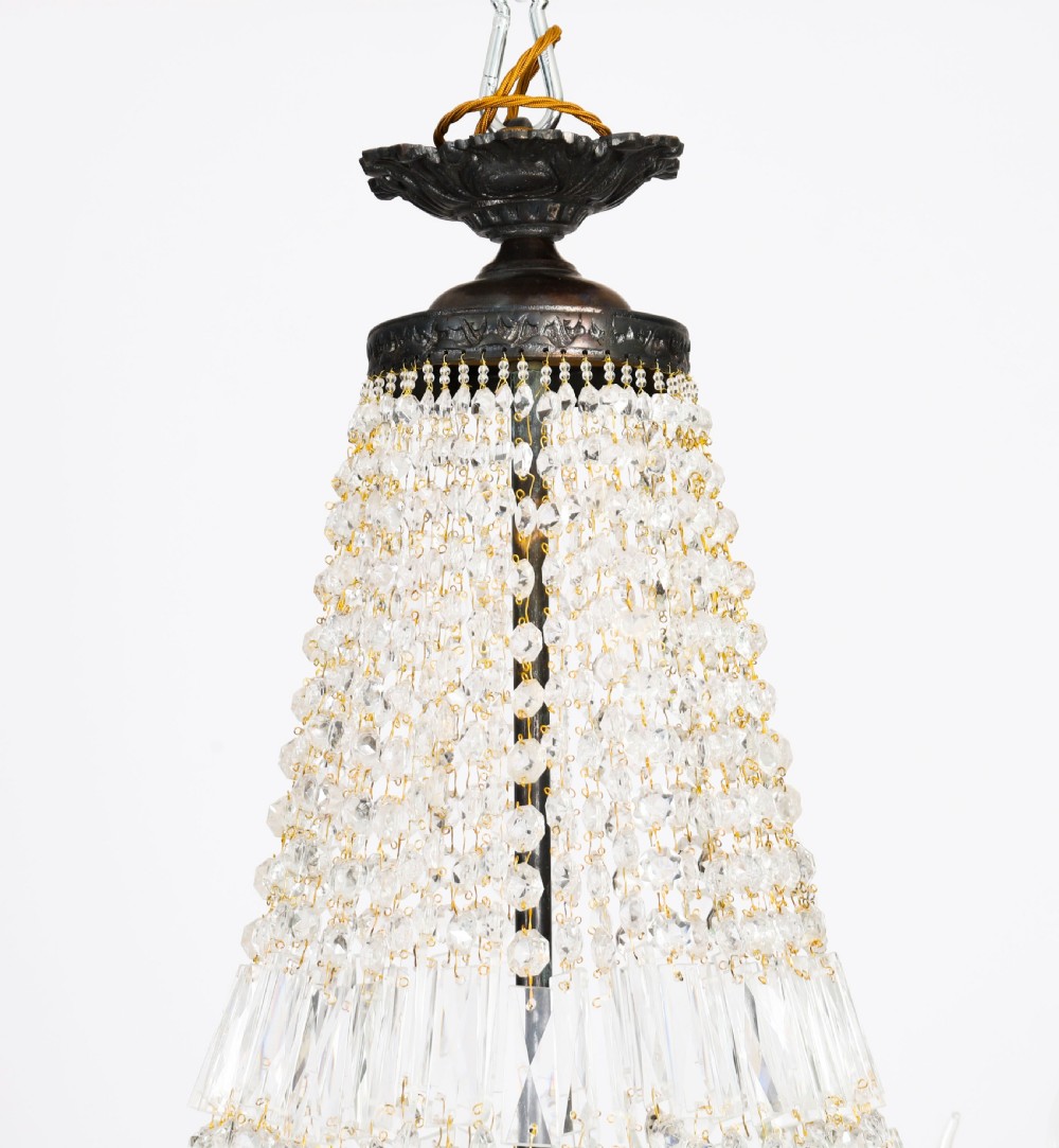 A pair of French Louis Revival tent and bag style chandeliers featuring tiered crystal bead cascades, dark bronze metal bands with floral festoons, and extending candle arms. View IX