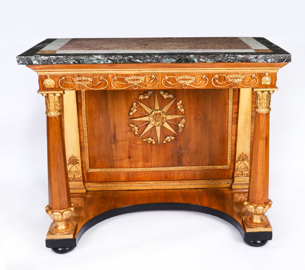 A French Empire walnut console table with a dark marble top, gold parcel gilt column supports, and a starburst motif panel. View II