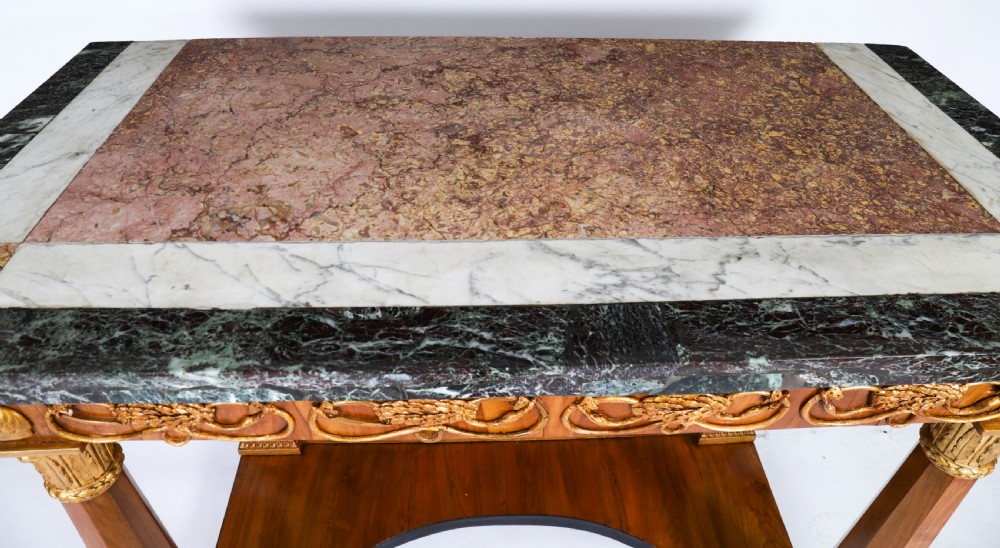 A French Empire walnut console table with a dark marble top, gold parcel gilt column supports, and a starburst motif panel. View IV