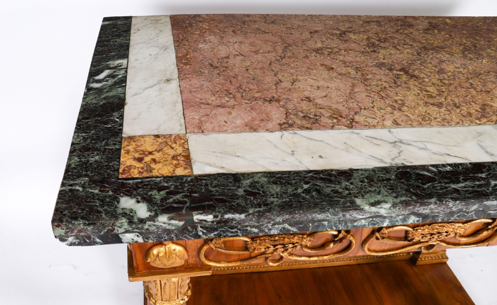 A French Empire walnut console table with a dark marble top, gold parcel gilt column supports, and a starburst motif panel. View V