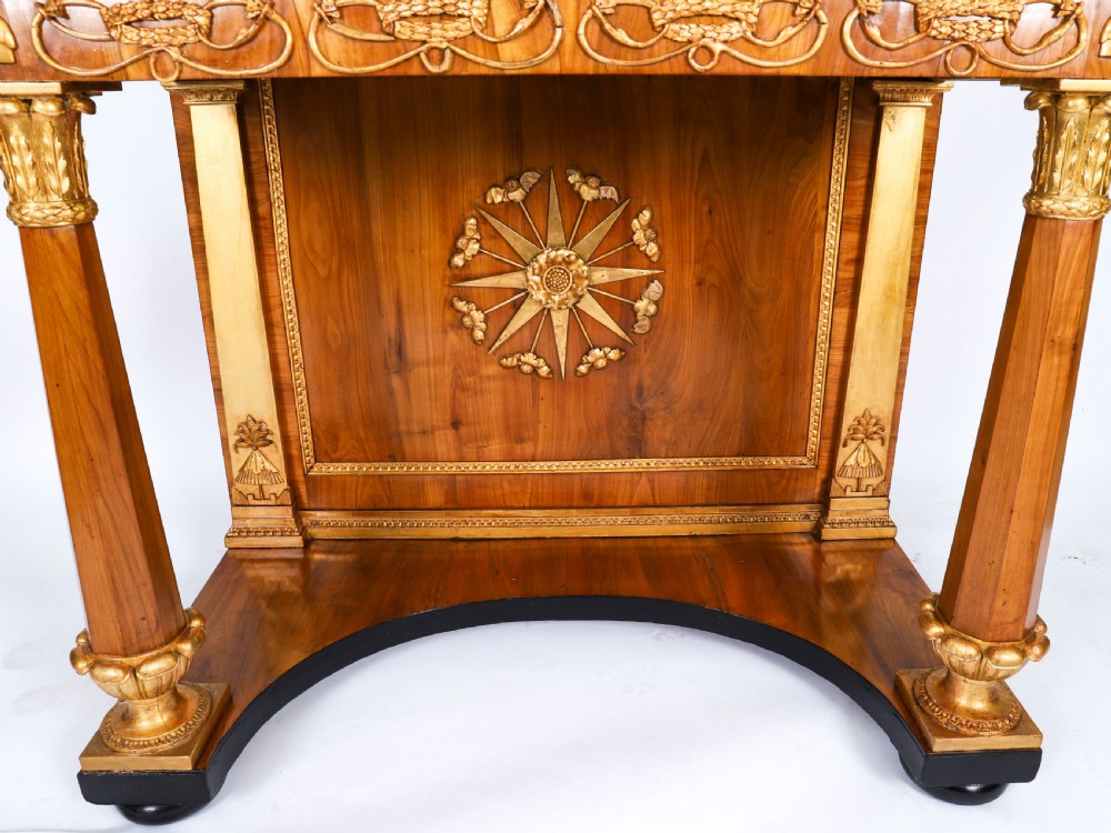 A French Empire walnut console table with a dark marble top, gold parcel gilt column supports, and a starburst motif panel. View VII