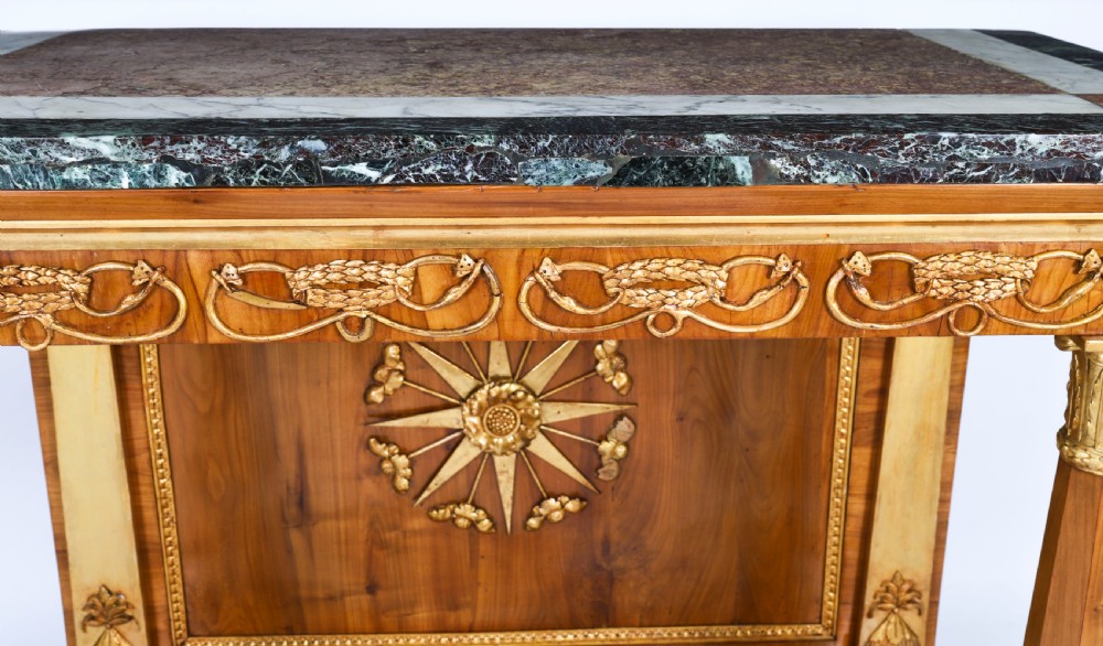 A French Empire walnut console table with a dark marble top, gold parcel gilt column supports, and a starburst motif panel. View IX