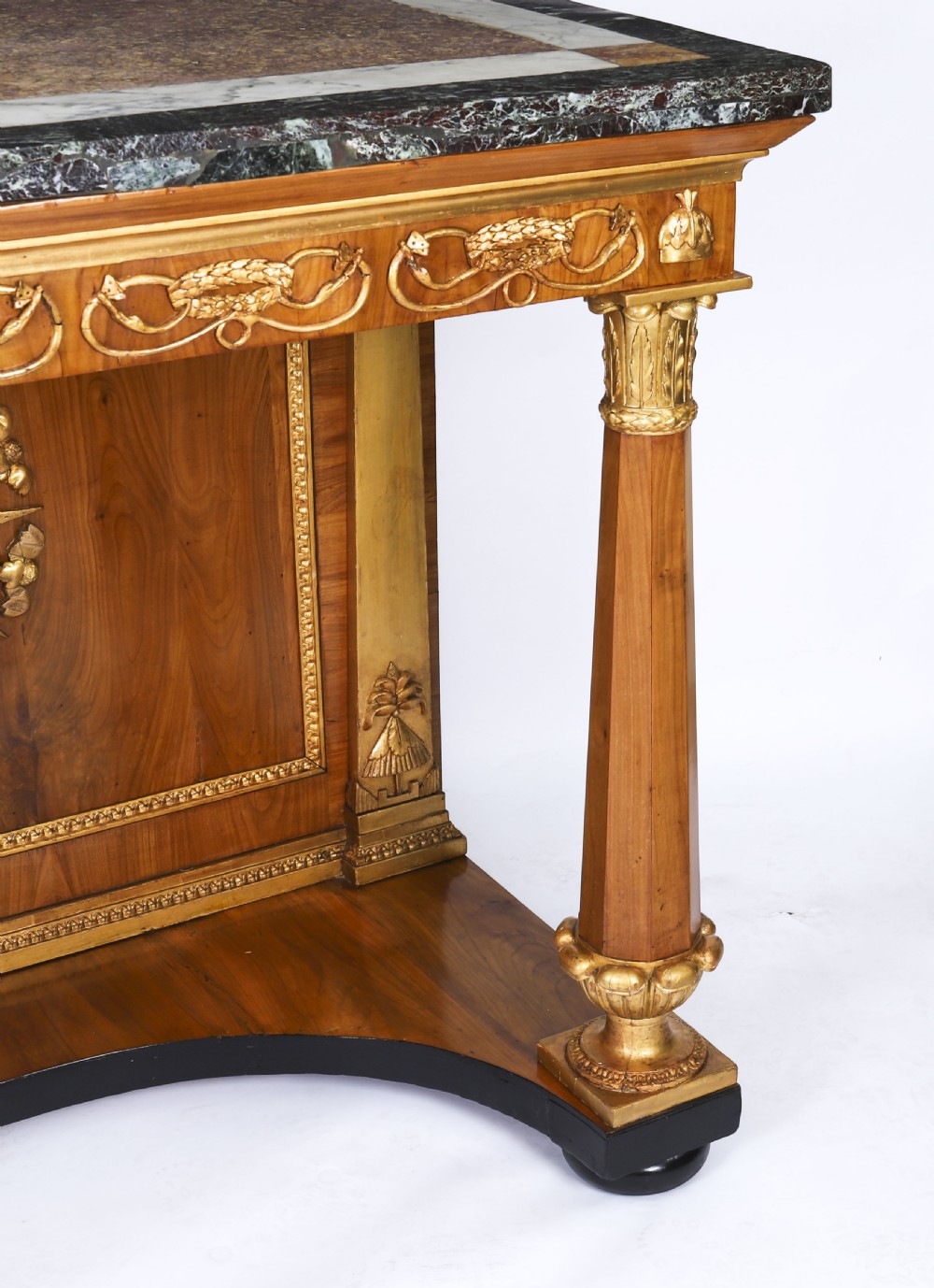 A French Empire walnut console table with a dark marble top, gold parcel gilt column supports, and a starburst motif panel. View XIV