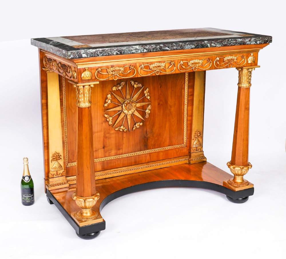 A French Empire walnut console table with a dark marble top, gold parcel gilt column supports, and a starburst motif panel. View XV