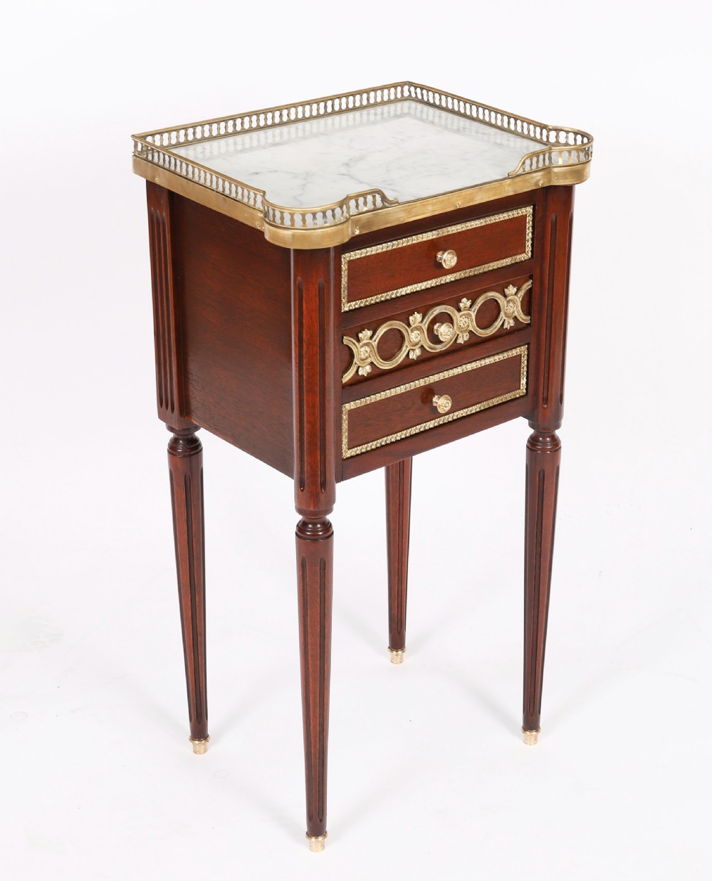 A pair of 19th-century mahogany French Empire bedside cabinets featuring white marble tops with pierced brass galleries, gilt bronze mounts, and slender fluted legs. View IV