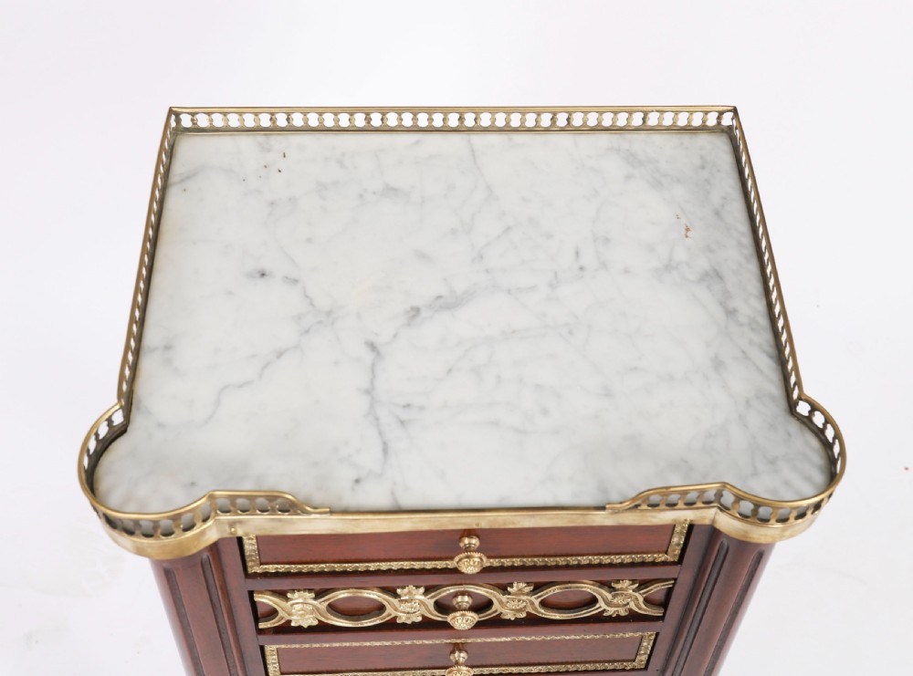 A pair of 19th-century mahogany French Empire bedside cabinets featuring white marble tops with pierced brass galleries, gilt bronze mounts, and slender fluted legs. View VIII
