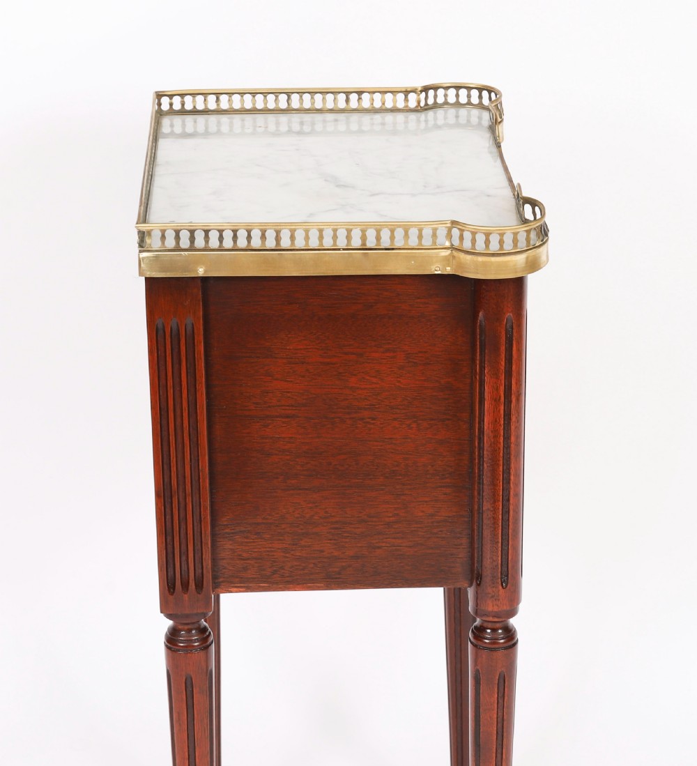 A pair of 19th-century mahogany French Empire bedside cabinets featuring white marble tops with pierced brass galleries, gilt bronze mounts, and slender fluted legs. View XI