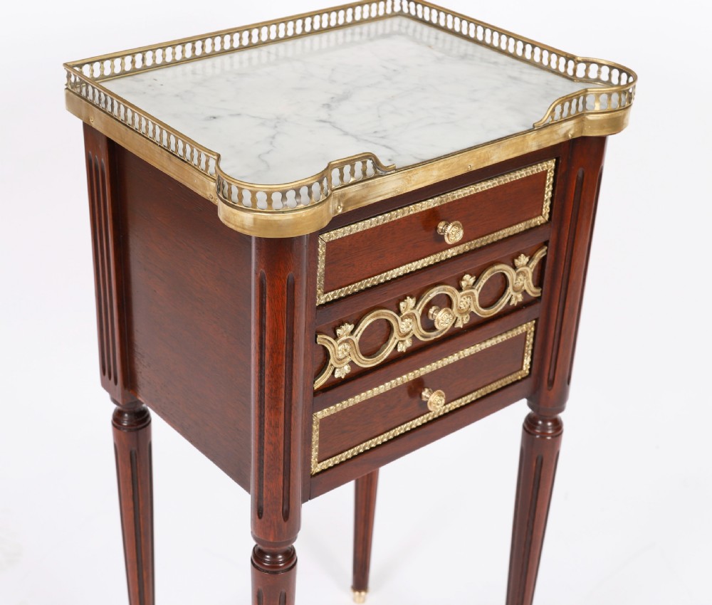 A pair of 19th-century mahogany French Empire bedside cabinets featuring white marble tops with pierced brass galleries, gilt bronze mounts, and slender fluted legs. View XIII
