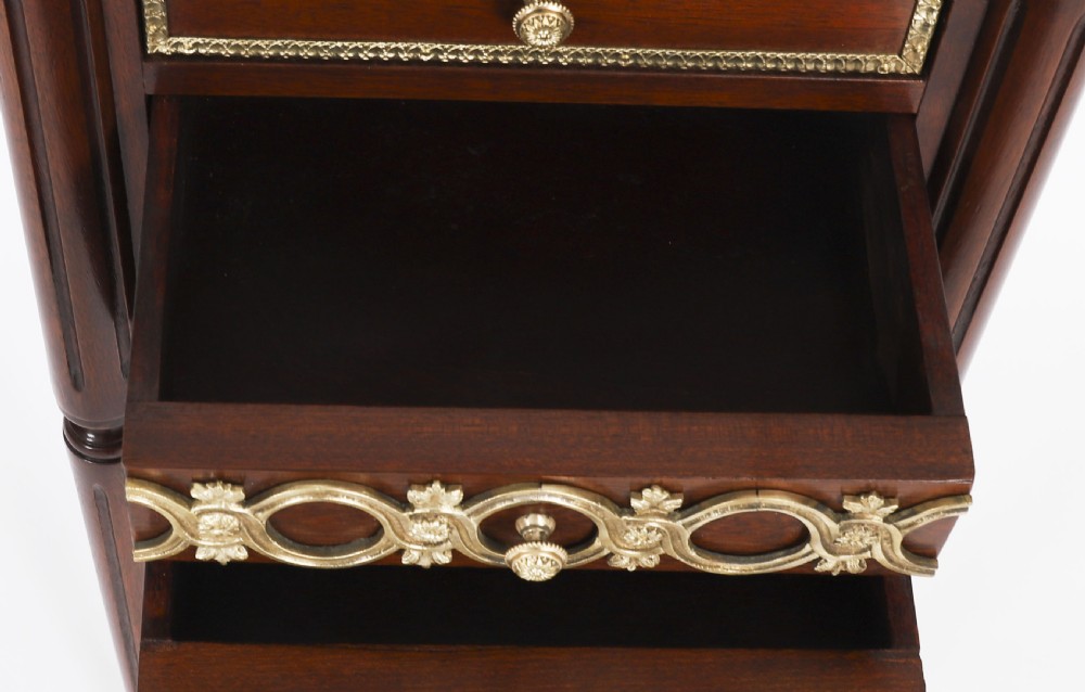 A pair of 19th-century mahogany French Empire bedside cabinets featuring white marble tops with pierced brass galleries, gilt bronze mounts, and slender fluted legs. View XVI