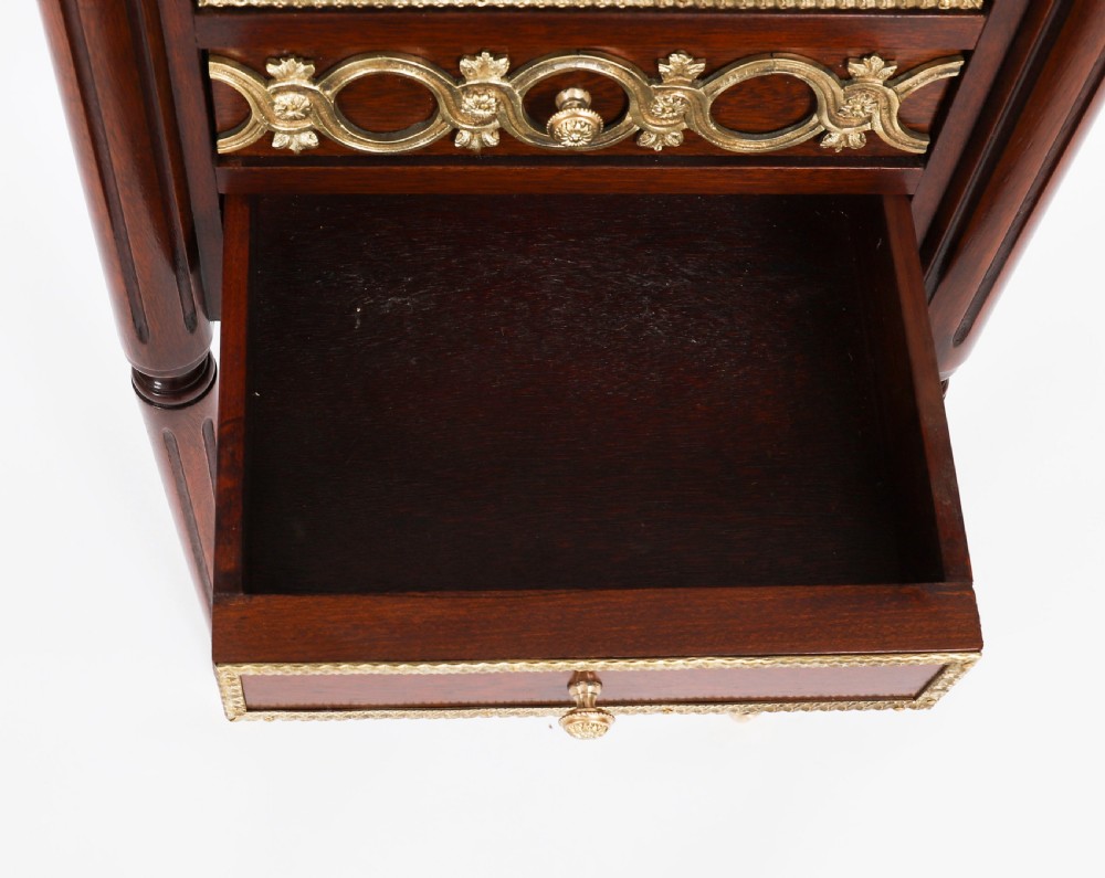 A pair of 19th-century mahogany French Empire bedside cabinets featuring white marble tops with pierced brass galleries, gilt bronze mounts, and slender fluted legs. View XVII