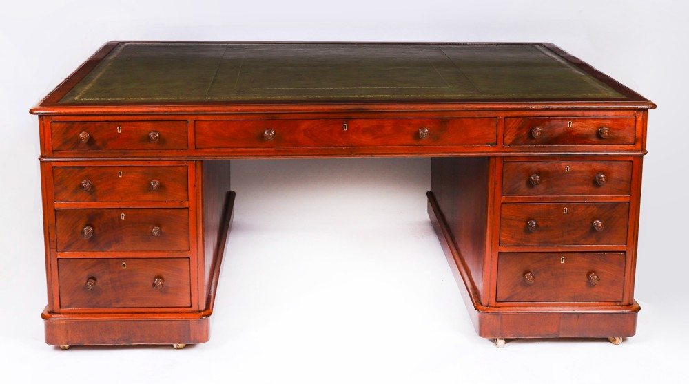 A Victorian flame mahogany partners pedestal desk fitted with a green leather inset top and wooden knob drawer pulls.