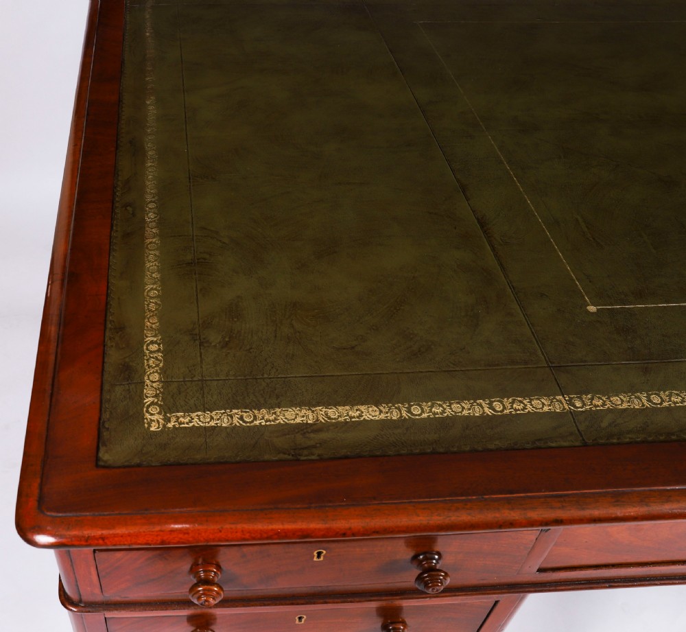 A Victorian flame mahogany partners pedestal desk fitted with a green leather inset top and wooden knob drawer pulls. View IV