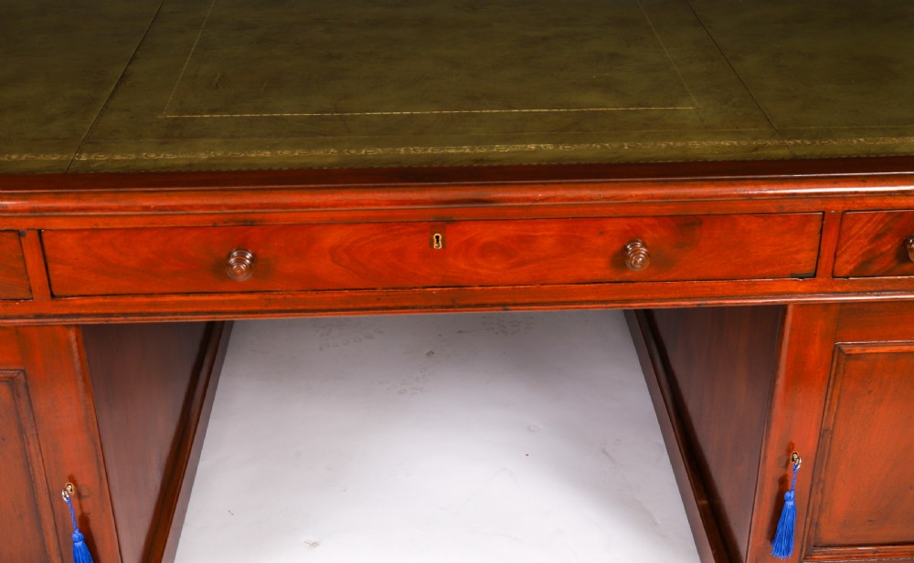A Victorian flame mahogany partners pedestal desk fitted with a green leather inset top and wooden knob drawer pulls. View V
