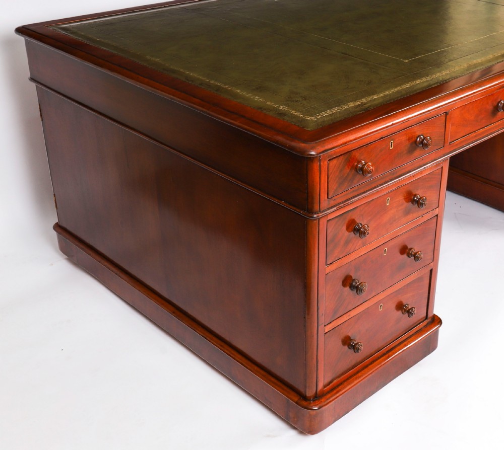 A Victorian flame mahogany partners pedestal desk fitted with a green leather inset top and wooden knob drawer pulls. View VI