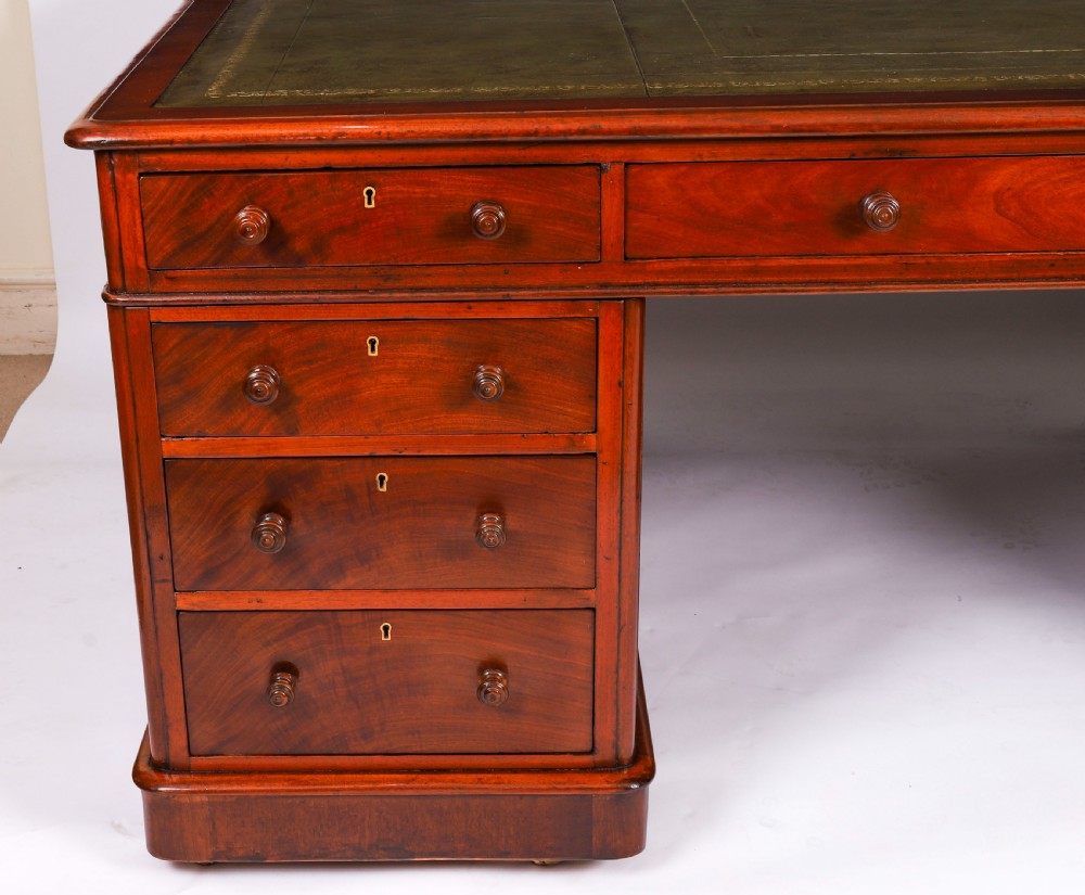 A Victorian flame mahogany partners pedestal desk fitted with a green leather inset top and wooden knob drawer pulls. View VII