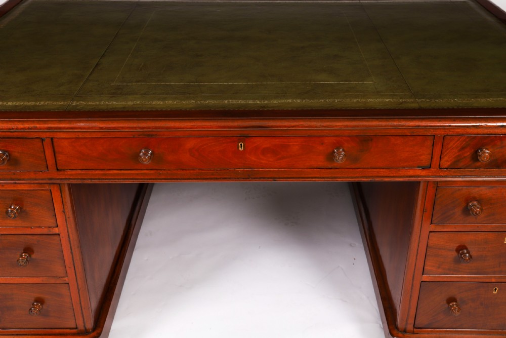 A Victorian flame mahogany partners pedestal desk fitted with a green leather inset top and wooden knob drawer pulls. View VIII