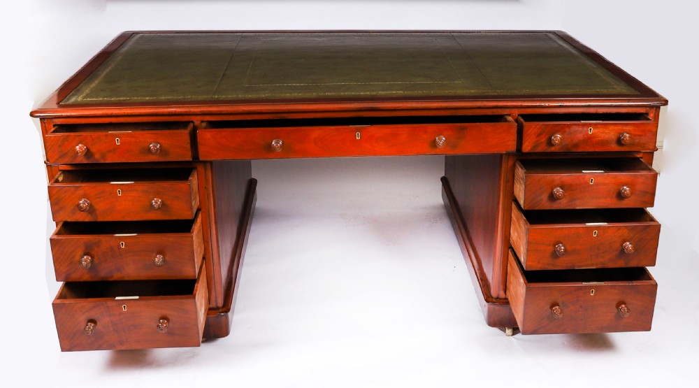 A Victorian flame mahogany partners pedestal desk fitted with a green leather inset top and wooden knob drawer pulls. View X