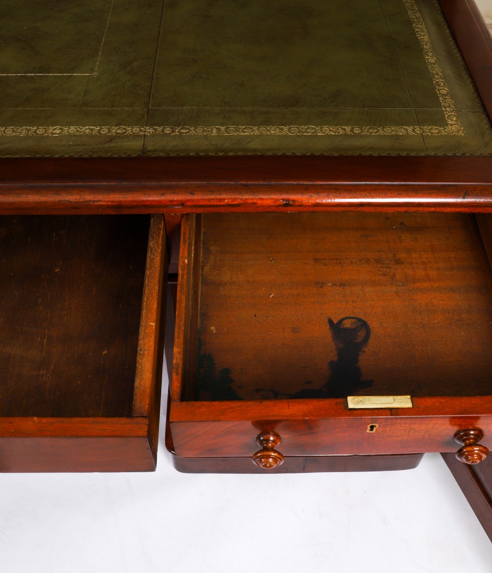 A Victorian flame mahogany partners pedestal desk fitted with a green leather inset top and wooden knob drawer pulls. View XII