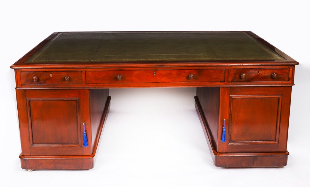 A Victorian flame mahogany partners pedestal desk fitted with a green leather inset top and wooden knob drawer pulls. View XV